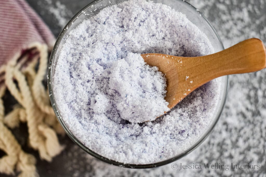 overhead view of a jar of homemade bath salts with a wood scoop