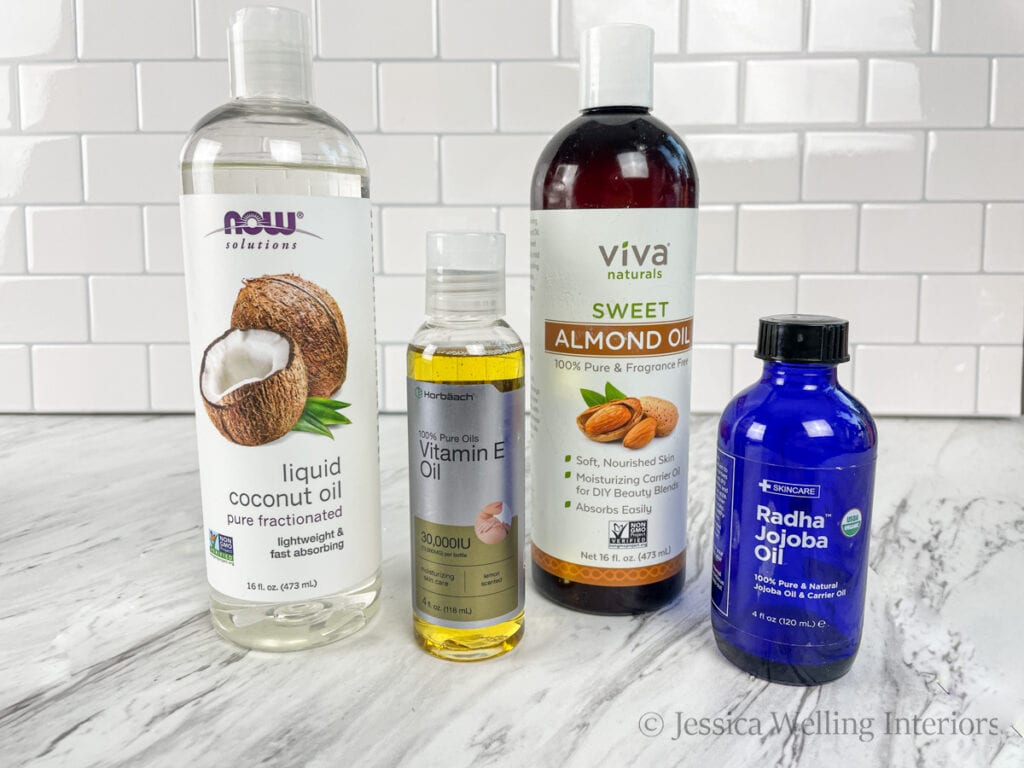 four different carrier oils on a countertop- fractionated coconut oil, vitamin E oil, sweet almond oil, and jojoba oil