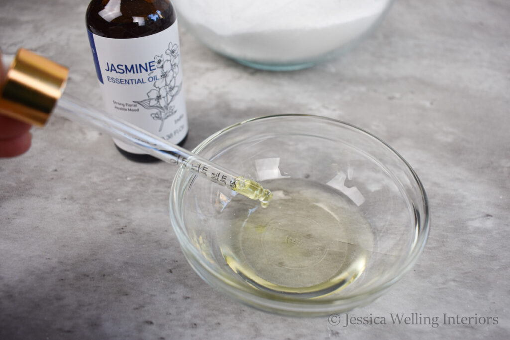 essential oils being added to a small bowl of carrier oil to make DIY fizzy bath salts