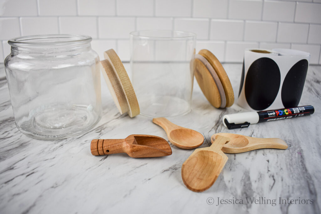 glass jars with airtight lids, chalkboard sticker labels, and a veriety of wood scoops for bath salts on a countertop