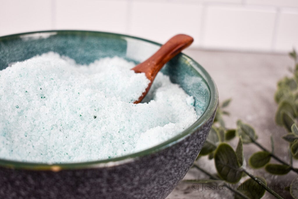 light green bath salts in a bowl with a wood scoop